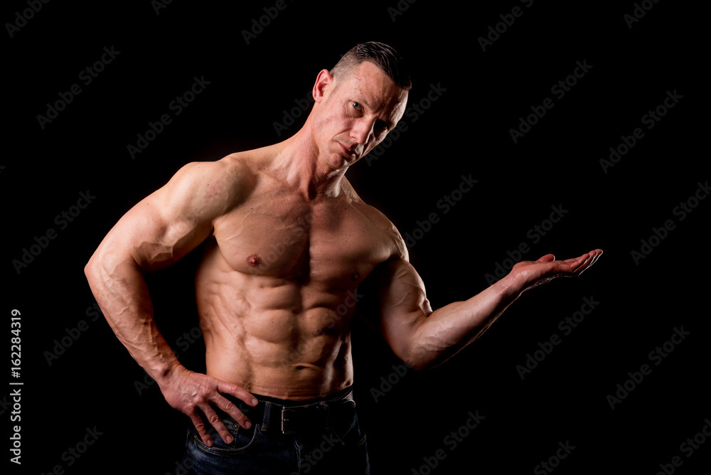 fit muscular man posing isolated on a dark background fit muscular man posing isolated on a dark background
