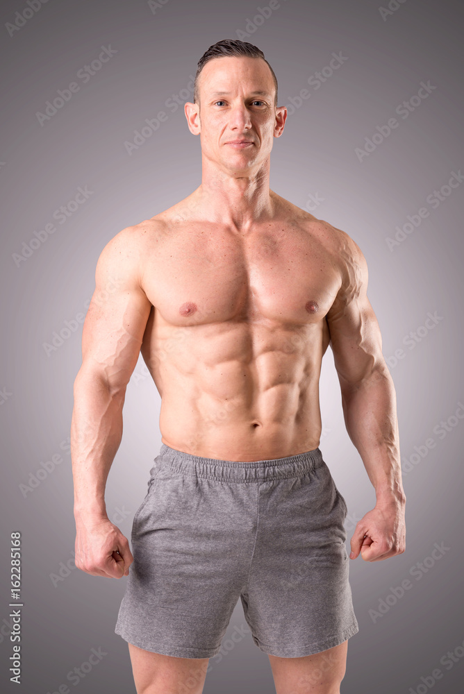fit muscular man posing isolated on a grey background fit muscular man posing isolated on a grey background