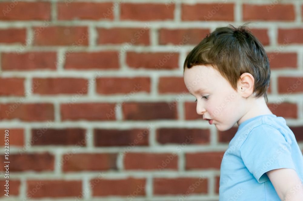 Young toddler boy in front of red birck wall Young toddler boy in front of red birck wall
