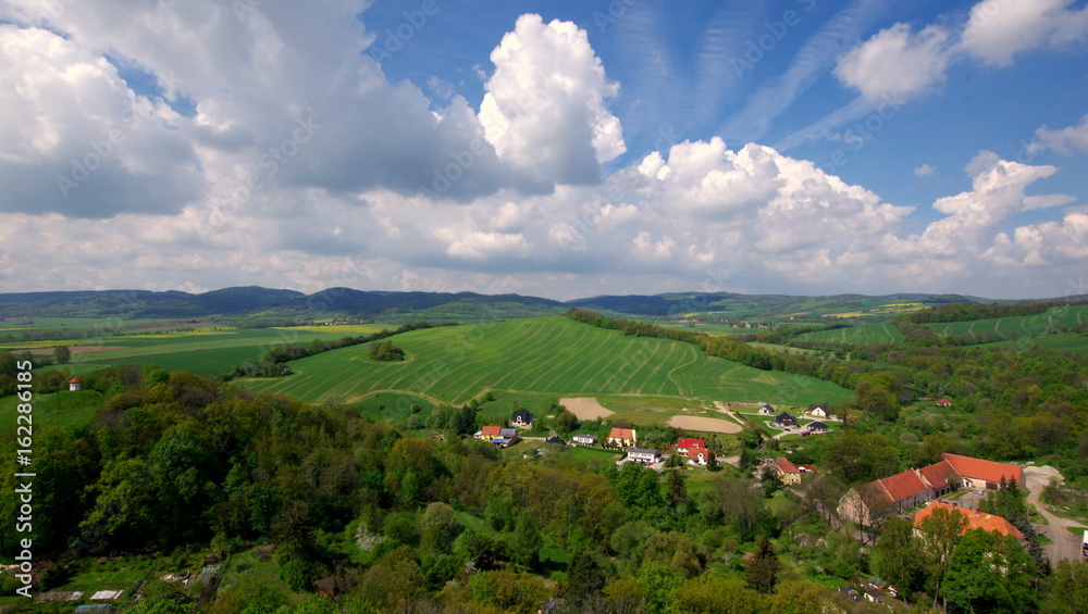 Naklejka premium Piękne białe chmury na niebieskim niebie nad polskimi polami, górami i wsiami