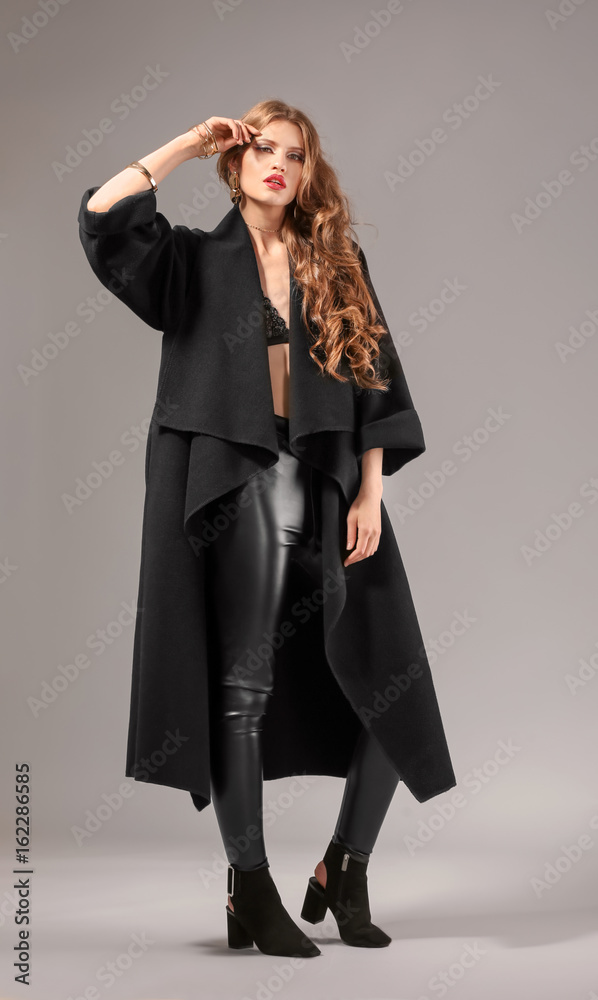 Beautiful stylish woman in dark coat on color background Beautiful stylish woman in dark coat on color background