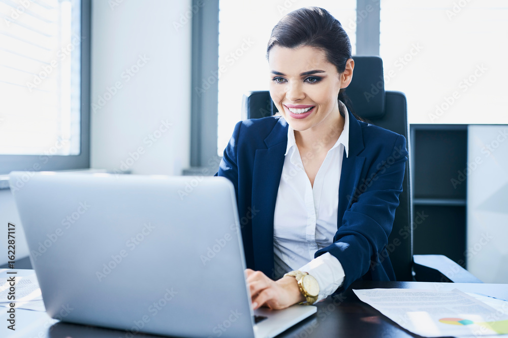 Smiling young businesswoman using laptop to work in her office Smiling young businesswoman using laptop to work in her office