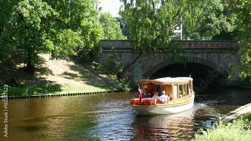 Small cruise ship sailing through the pilsetas kanals in the Bastion Hill Park Riga, Latvia photo