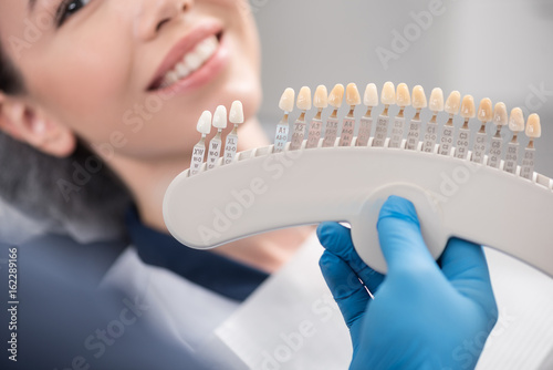 Odontologist arms showing teeth implants to patient photo