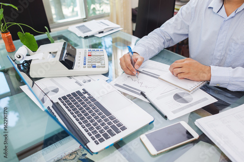 Business man working on laptop and analysis data on paper during working at home office