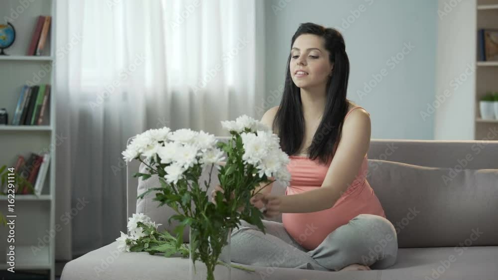 Lovely pregnant girl decorating house with nice flowers, aesthetic enjoyment Lovely pregnant girl decorating house with nice flowers, aesthetic enjoyment