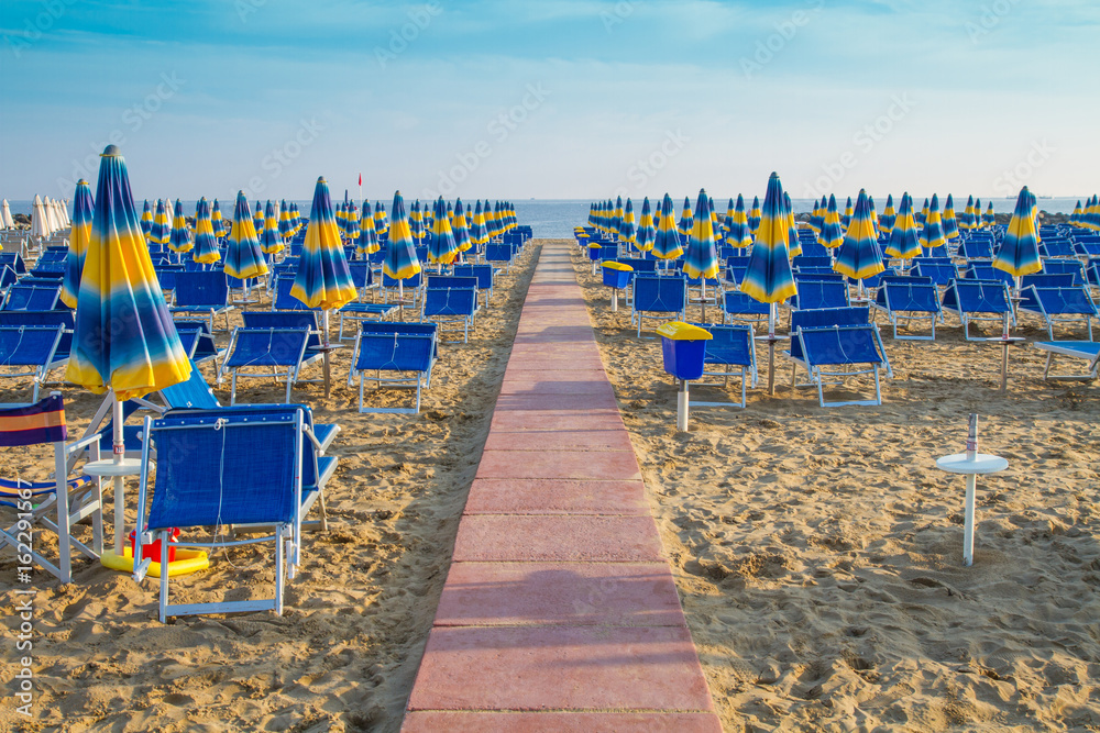 Fototapeta premium Sunrise beach with sun loungers and umbrellas