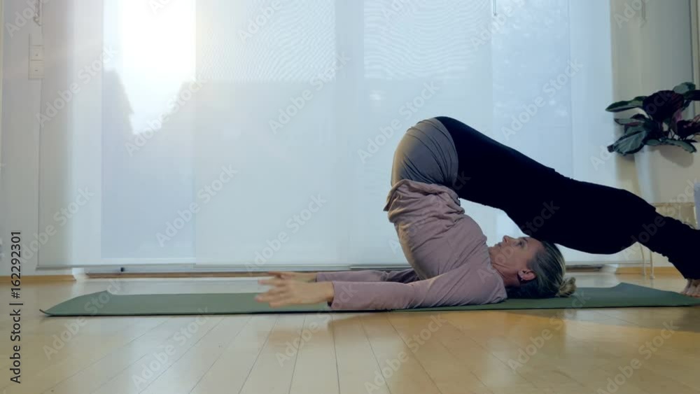 A woman performs the plow pose yoga position. A woman performs the plow pose yoga position.