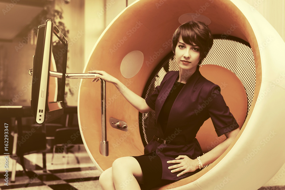 Fototapeta premium Young fashion business woman sitting on computer chair in office