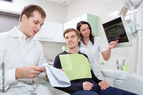 Male patient and dentist with assistant during check in at dental clinic