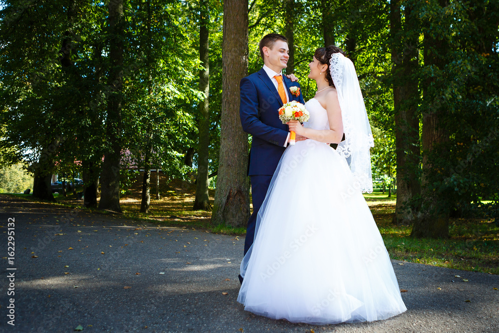 Young wedding couple with bouquet at forest background