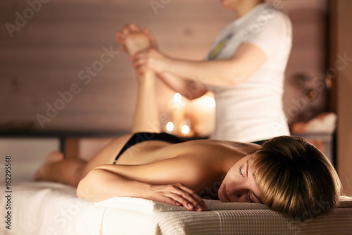 Young woman having feet massage in beauty spa salon, close up