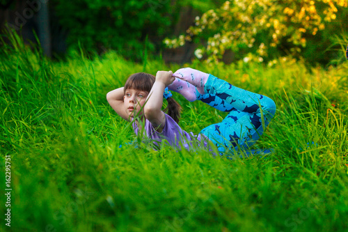 beautiful girl doing yoga outdoors On green grass photo