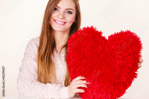 Happy woman holding heart shaped pillow