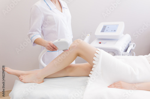 Woman on laser hair removal procedure at beauty salon photo