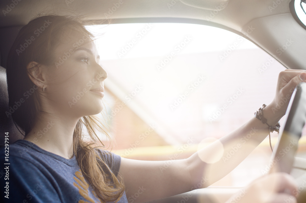 The beautiful girl the driver is traveling in his car on a Sunny day. The wind blows in her face and develops hair