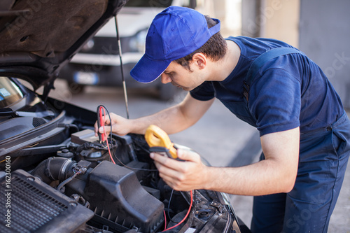 Car electrician troubleshooting a car engine © Minerva Studio