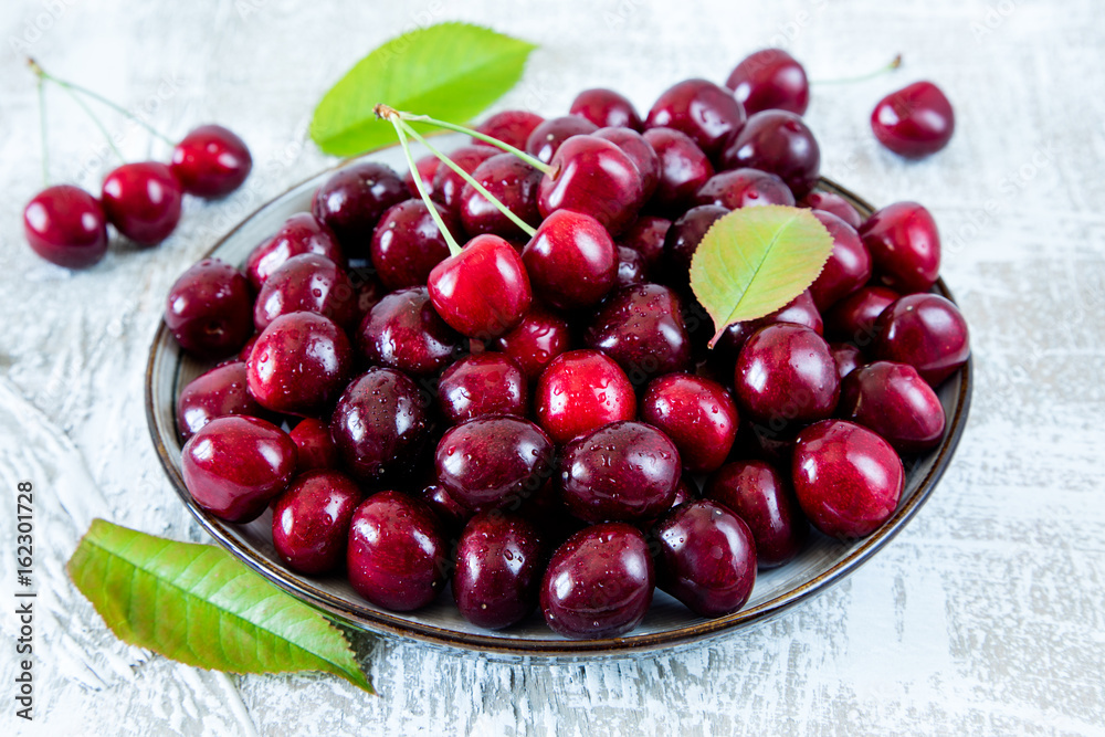 Fresh cherry on plate on wooden blue background. fresh ripe cherries. sweet cherries Fresh cherry on plate on wooden blue background. fresh ripe cherries. sweet cherries