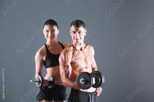 Athletic man and woman with a dumbells. Personal fitness instructor. Personal training.