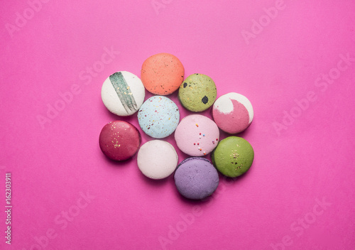 Small multicolored appetizing maccarone cakes lined with a pile on a pink background photo