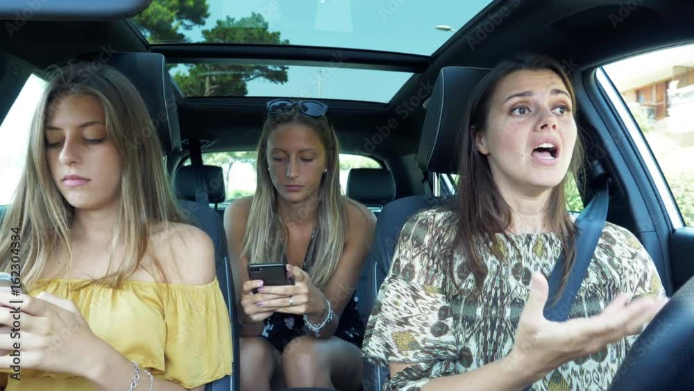 Mother driving car trying to talk to daughters messaging and texting with cell phone addicted slow motion
