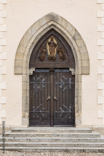 Large wooden door with wrought-iron elements. Decorative door with fittings.