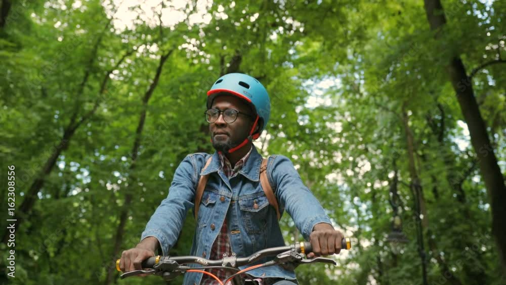 Portrait of happy african man in helment and glasses cycling in the park and feeling happy. Portrait of happy african man in helment and glasses cycling in the park and feeling happy.