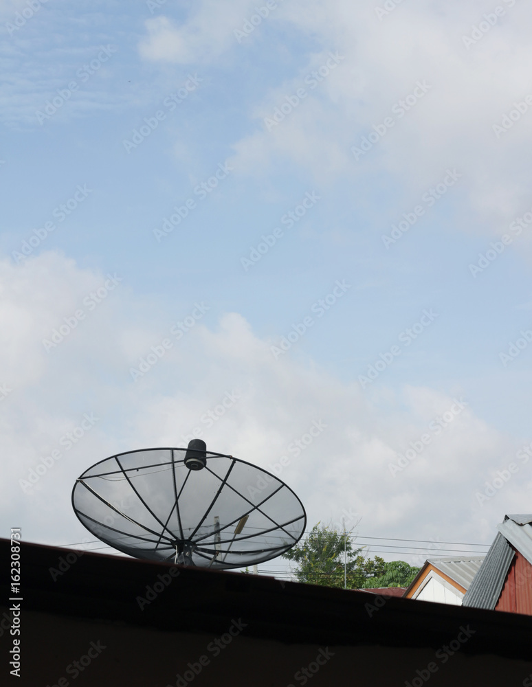 An old and rusty television antenna against a cloudy blue sky.