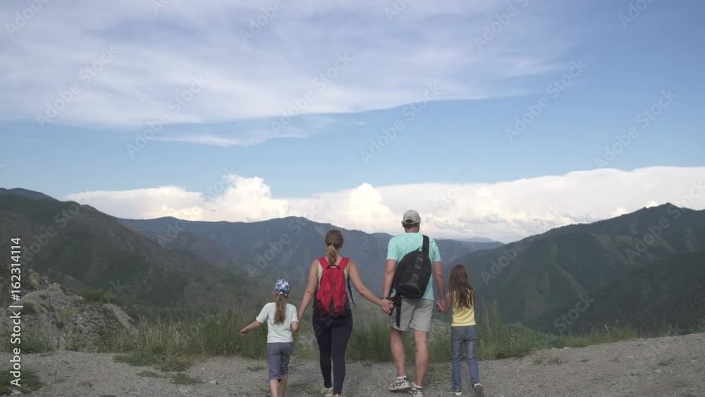 family of tourists traveling in the mountains. parents and children spend time outdoors. father, mother and two daughters went camping family of tourists traveling in the mountains. parents and children spend time outdoors. father, mother and two daughters went camping
