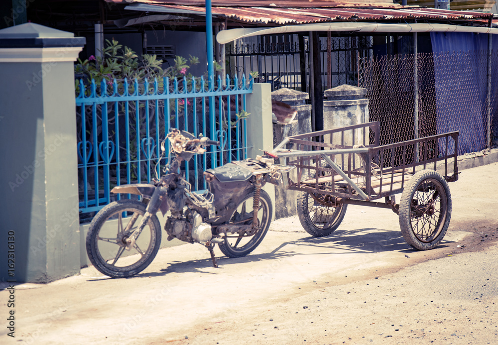 Motobike in the Vietnamese village, adapted for cargo transportation. A picturesque village street. With toning
