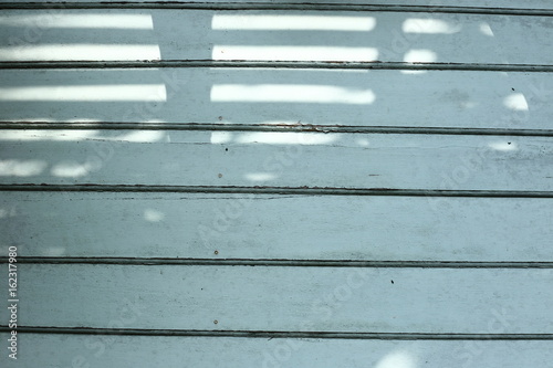 a wooden wall faded blue color background with sunlight and shadow