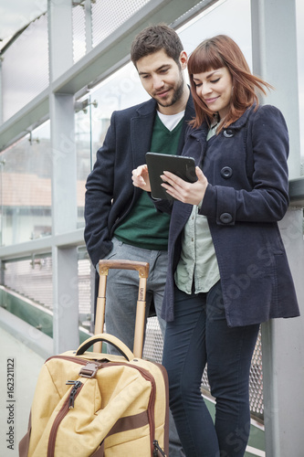 Young couple in airport building using digital tablet