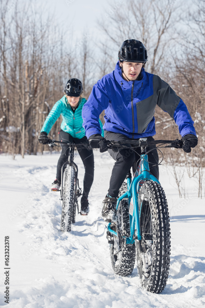 Attractive couple riding fat bikes in the snow
