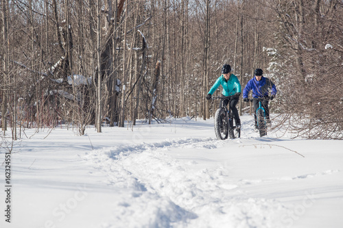 Attractive couple riding fat bikes in the snow