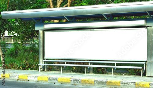 The white sign board on the bus stop wiih green tree background near old road photo