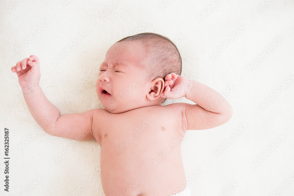 Adorable little newborn baby lying and crying on the bed Adorable little newborn baby lying and crying on the bed
