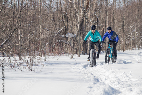 Obraz na płótnie Attractive couple riding fat bikes in the snow w salonie