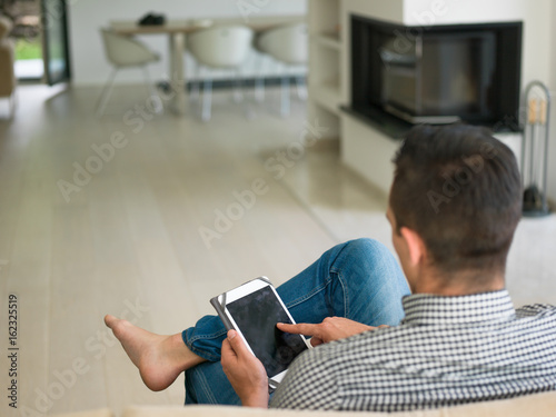 man on sofa using tablet computer