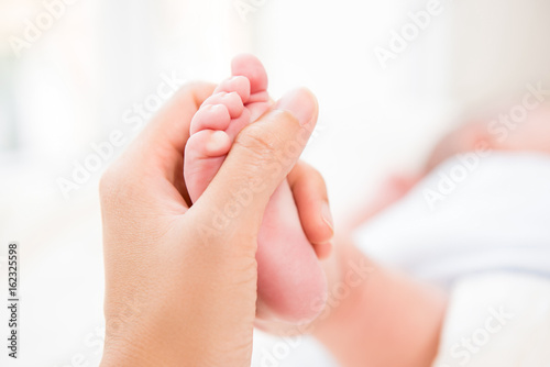 Mother hand gently touch small baby foot