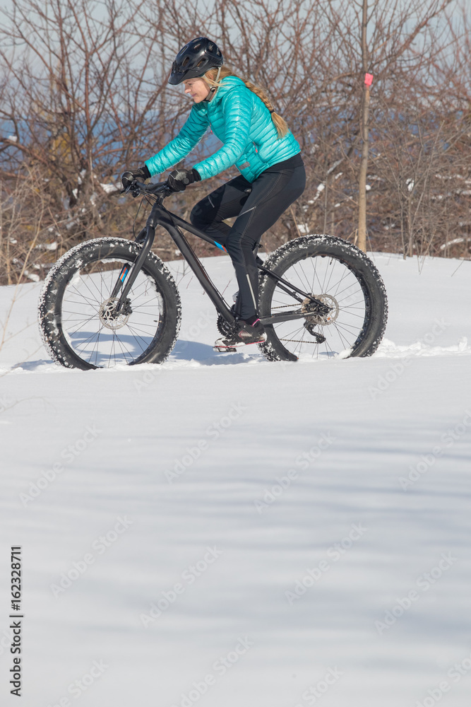 Beautiful woman riding her fat bike in the snow