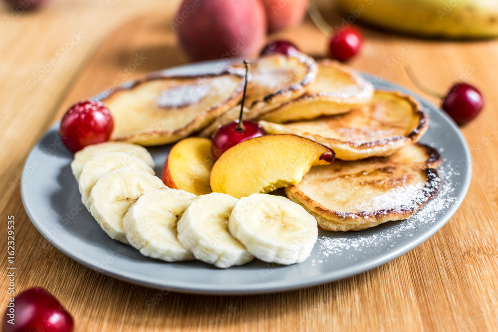 Sweet pancakes with berries and fruits on a wooden background
