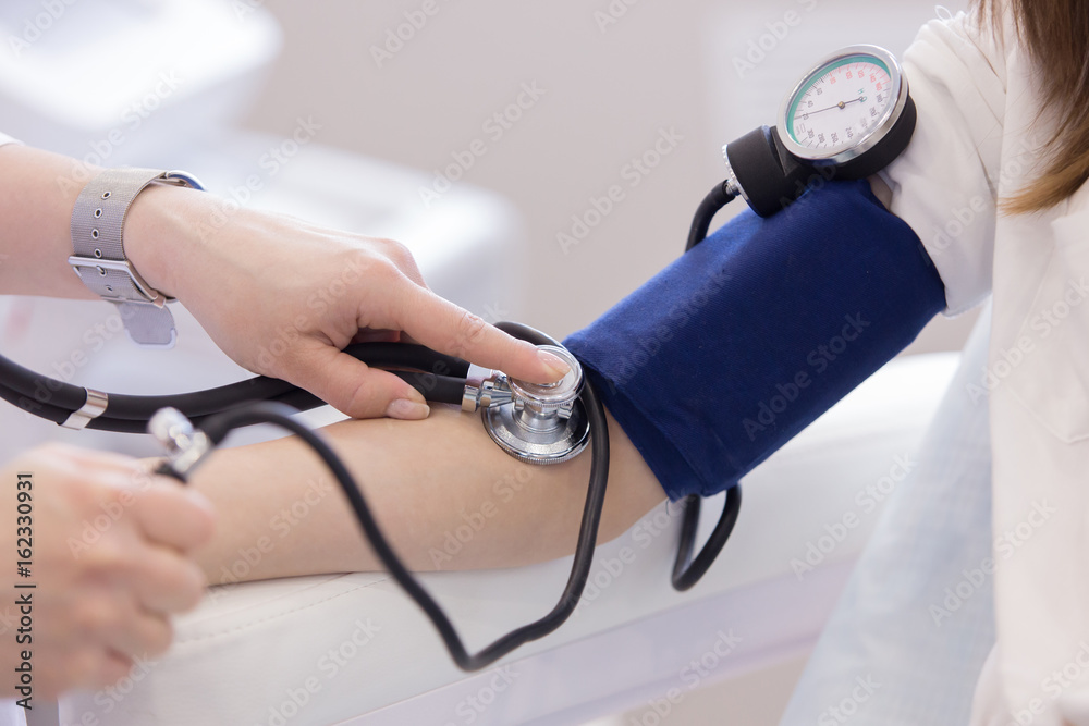 doctor measuring blood pressure from her patient close up - obrazy, fototapety, plakaty 