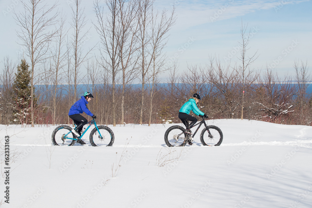 Attractive couple riding fat bikes in the snow