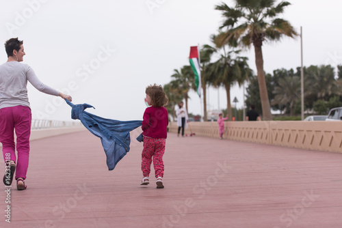 mother and cute little girl on the promenade by the sea