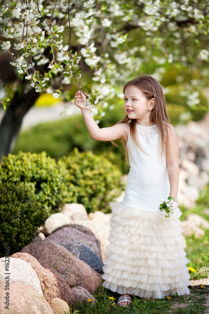 Prettyl smiling little girl in cream dressin the blossom garden Prettyl smiling little girl in cream dressin the blossom garden