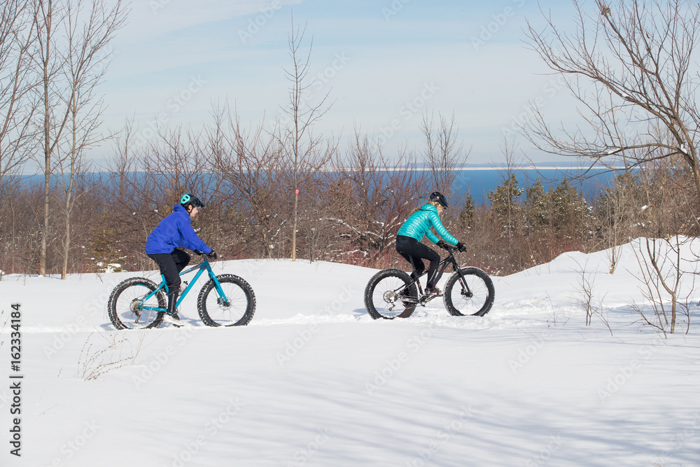 Attractive couple riding fat bikes in the snow