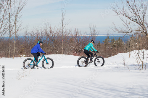 Obraz na płótnie Attractive couple riding fat bikes in the snow w salonie