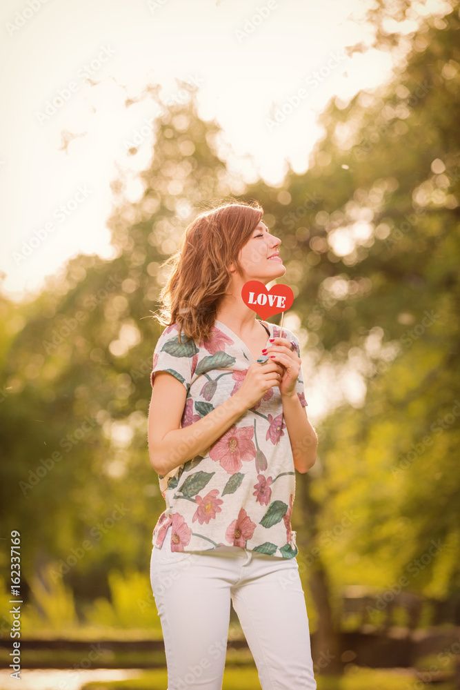 Girl posing with heart - shaped love sign.