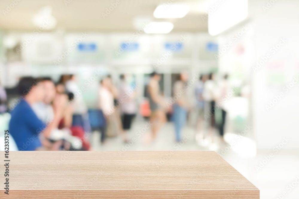 Wood table top (or counter) on blur background of people in hospital lobby