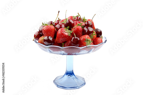 Schilderij op canvas Strawberries and cherries in glass stand isolated on white background